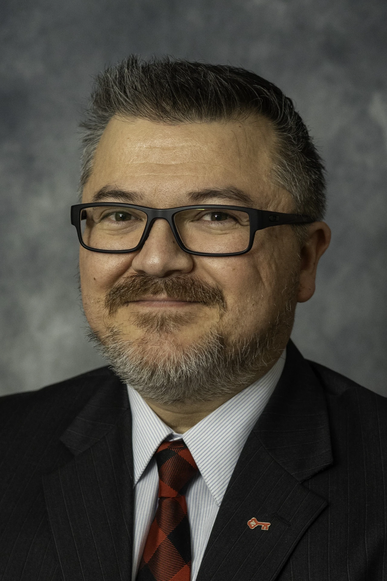 Professional corporate headshot of a man in a pinstripe suit and red tie, photographed by Rebecca Lamont